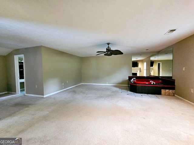 unfurnished living room featuring ceiling fan, vaulted ceiling, a textured ceiling, and carpet flooring