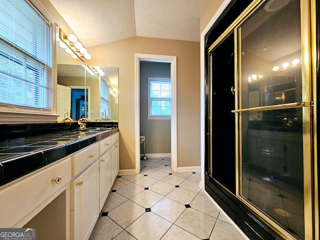 bathroom featuring walk in shower, tile flooring, a textured ceiling, vanity with extensive cabinet space, and vaulted ceiling