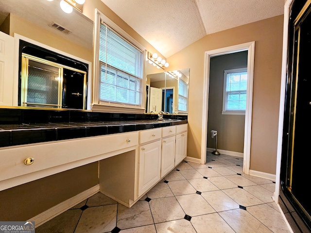 bathroom featuring vaulted ceiling, dual vanity, tile floors, and a textured ceiling