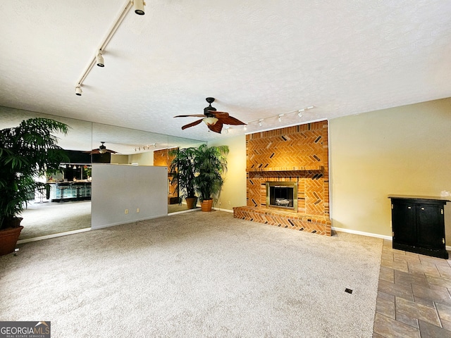 unfurnished living room featuring carpet flooring, a fireplace, ceiling fan, track lighting, and a textured ceiling