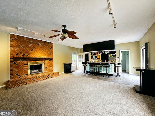 unfurnished living room with ceiling fan, light carpet, a textured ceiling, track lighting, and indoor bar