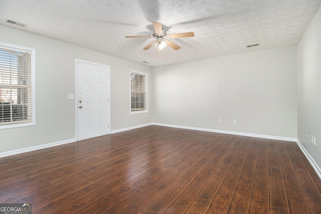 empty room featuring a textured ceiling, ceiling fan, and dark wood-type flooring