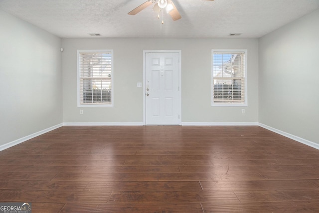 interior space featuring a textured ceiling, dark hardwood / wood-style flooring, a wealth of natural light, and ceiling fan