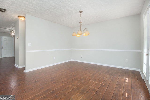 empty room with ceiling fan with notable chandelier, dark wood-type flooring, and a textured ceiling