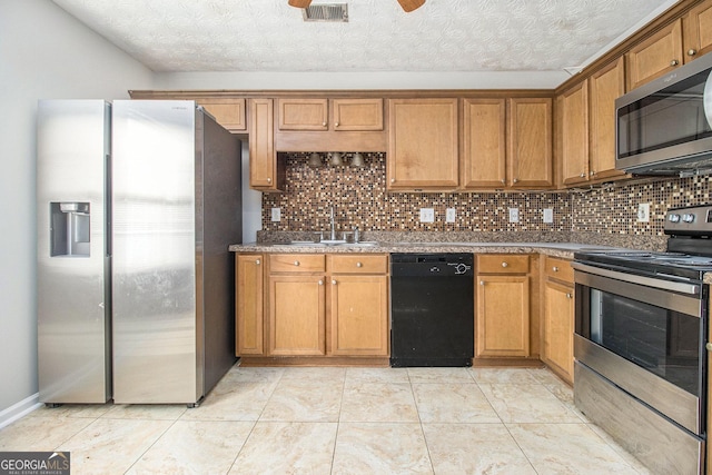 kitchen featuring decorative backsplash, a textured ceiling, stainless steel appliances, sink, and light tile patterned floors