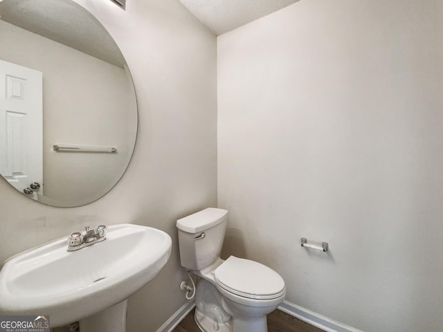 bathroom featuring hardwood / wood-style flooring, toilet, sink, and a textured ceiling