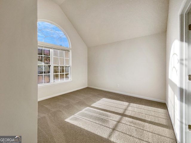 empty room with carpet floors and vaulted ceiling