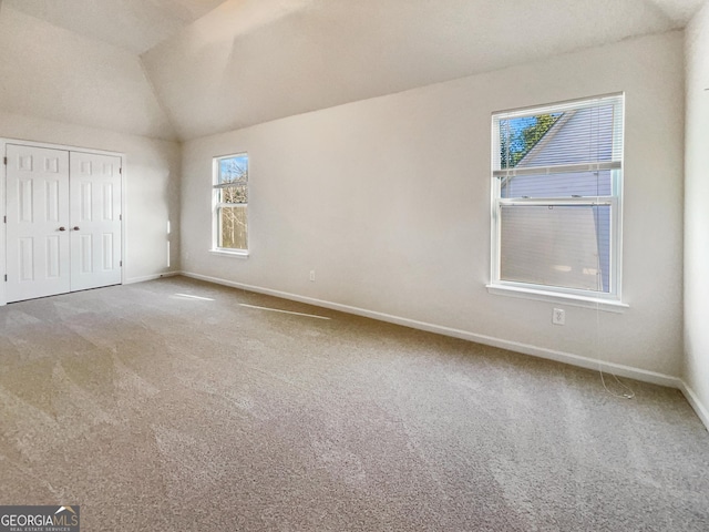 unfurnished bedroom with carpet flooring, vaulted ceiling, and a closet