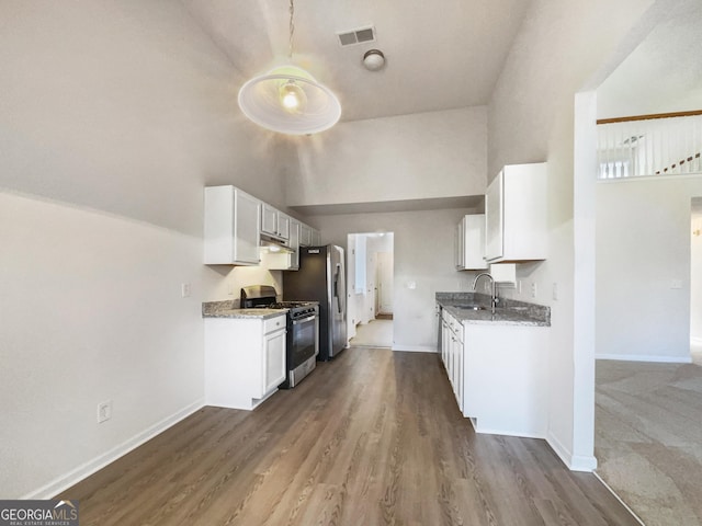 kitchen with light stone countertops, appliances with stainless steel finishes, hardwood / wood-style flooring, and white cabinetry