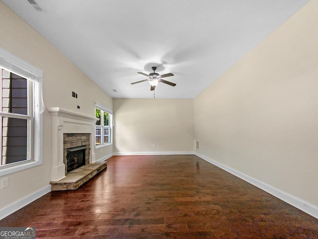 unfurnished living room with a fireplace, ceiling fan, and dark wood-type flooring