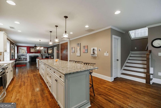 kitchen with a kitchen island, white cabinets, a kitchen breakfast bar, hanging light fixtures, and crown molding