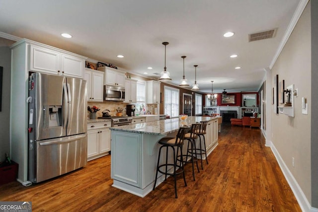 kitchen featuring white cabinetry, appliances with stainless steel finishes, a breakfast bar area, and hanging light fixtures