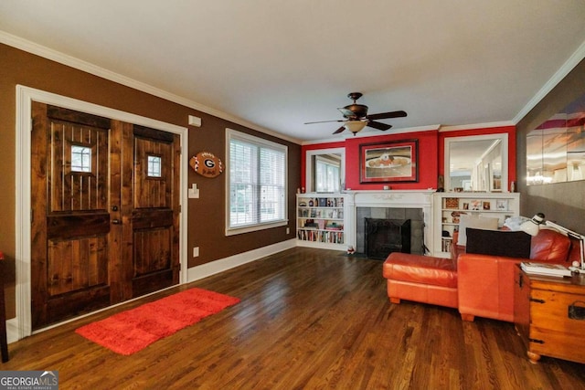 living room with a tiled fireplace, ornamental molding, dark wood-type flooring, and ceiling fan