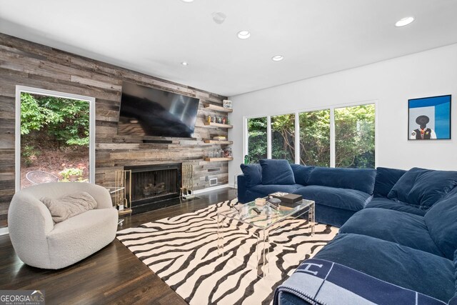 living room featuring dark hardwood / wood-style floors, a fireplace, and wood walls