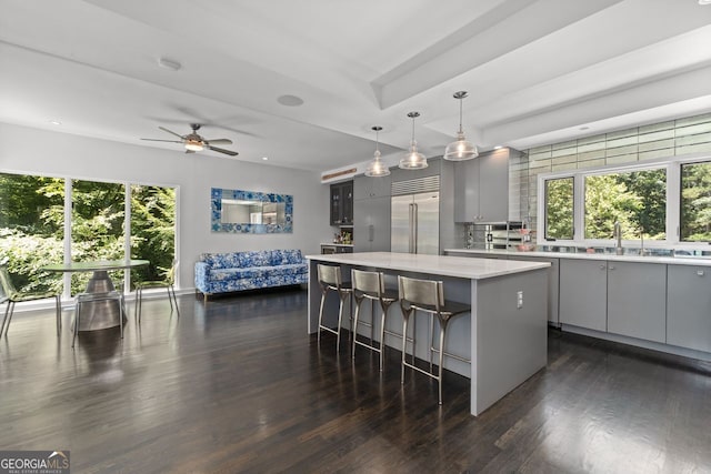 kitchen featuring hanging light fixtures, built in fridge, gray cabinetry, a center island, and dark wood-type flooring