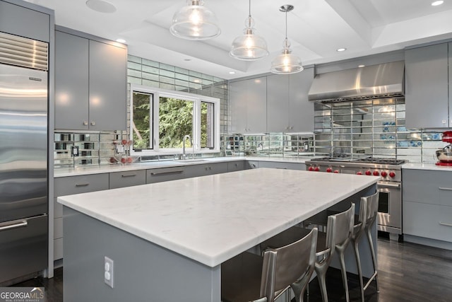 kitchen featuring premium appliances, a kitchen island, gray cabinets, and backsplash