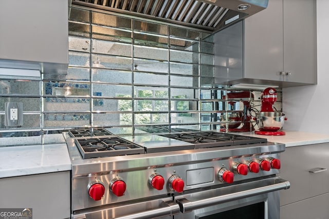 kitchen with custom range hood, gray cabinets, tasteful backsplash, and range with two ovens