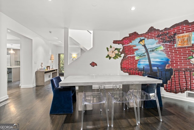 dining space featuring dark hardwood / wood-style flooring and brick wall