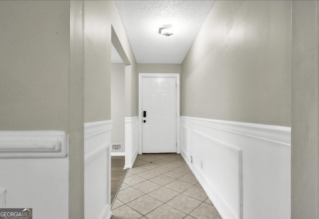 doorway to outside with light tile patterned floors and a textured ceiling