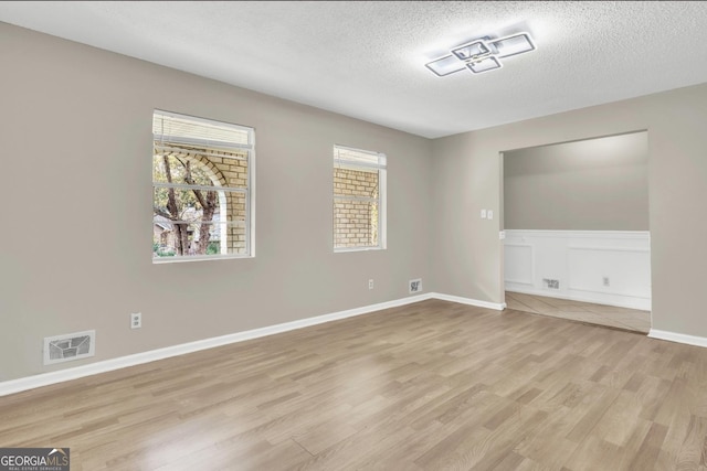 empty room featuring a textured ceiling and light wood-type flooring