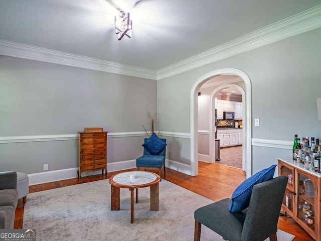 living area with ornamental molding and light hardwood / wood-style flooring