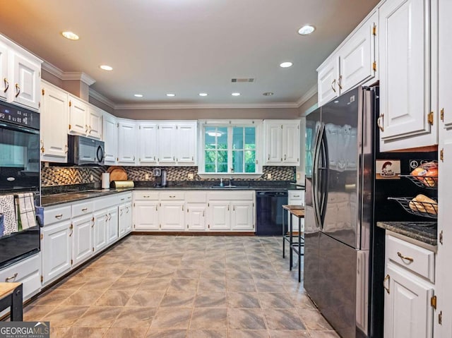 kitchen featuring dark stone counters, ornamental molding, sink, black appliances, and white cabinetry