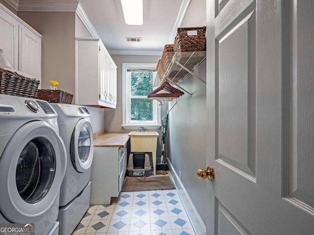 laundry room featuring cabinets, washing machine and dryer, and ornamental molding