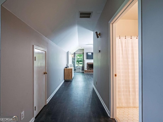 hallway featuring dark wood-type flooring and vaulted ceiling