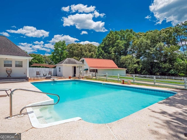 view of pool featuring a diving board, an outbuilding, and a patio