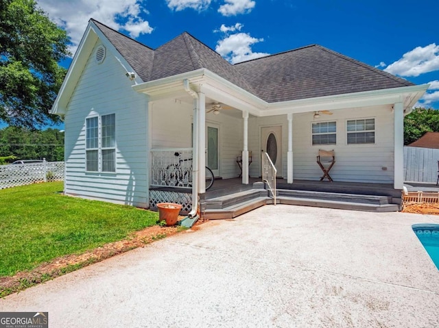 view of front of property with a front yard, a swimming pool, ceiling fan, and covered porch