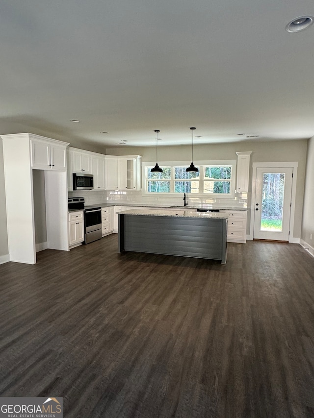 kitchen featuring appliances with stainless steel finishes, dark hardwood / wood-style floors, hanging light fixtures, a center island, and white cabinets