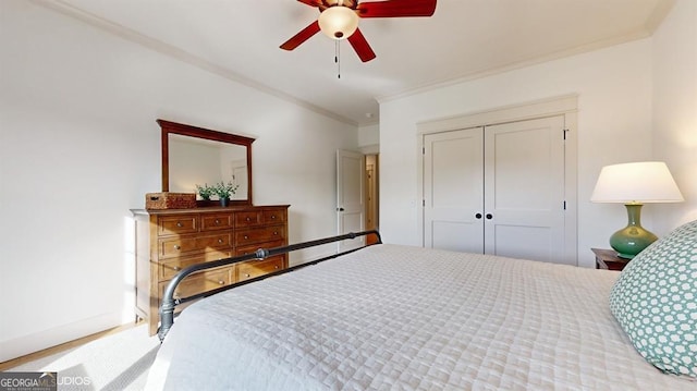 carpeted bedroom with ceiling fan, crown molding, and a closet