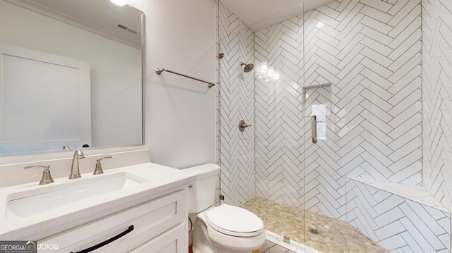 bathroom with a tile shower, vanity, toilet, and ornamental molding