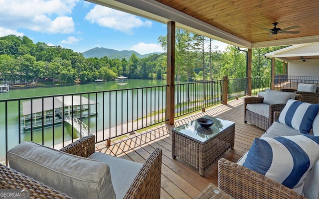 deck featuring ceiling fan, a water and mountain view, and an outdoor living space