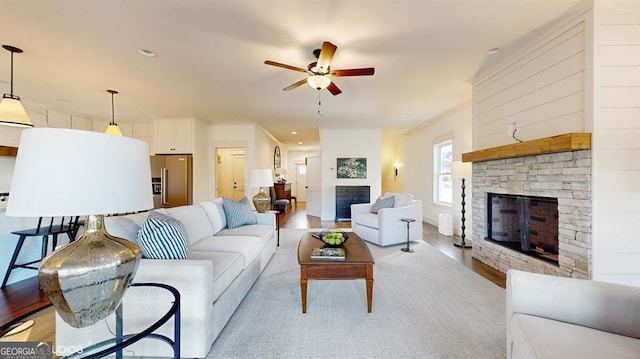 living room featuring ceiling fan, a fireplace, and light hardwood / wood-style flooring