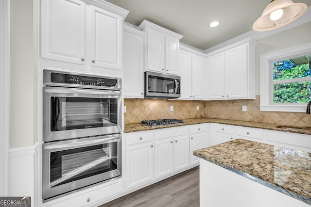 1216 Trophy Club Ave, Dacula, GA 30019 - kitchen with appliances with stainless steel finishes, white cabinetry, dark stone counters, and backsplash