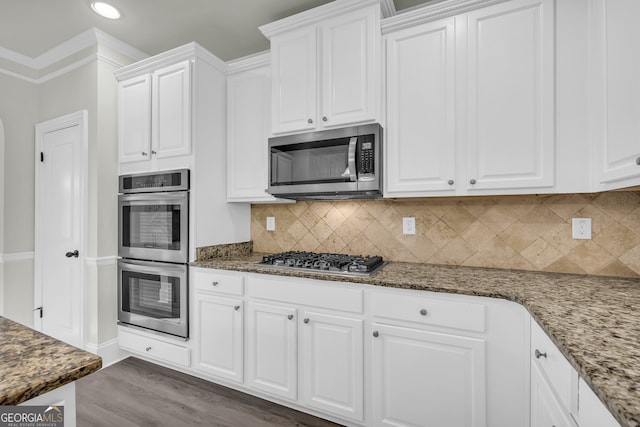 1216 Trophy Club Ave, Dacula, GA 30019 - kitchen featuring dark hardwood / wood-style flooring, stainless steel appliances, backsplash, white cabinetry, and ornamental molding