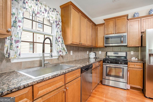 kitchen featuring appliances with stainless steel finishes, light wood-type flooring, tasteful backsplash, ornamental molding, and sink