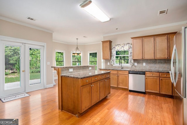 kitchen with ornamental molding, stainless steel appliances, sink, pendant lighting, and a center island