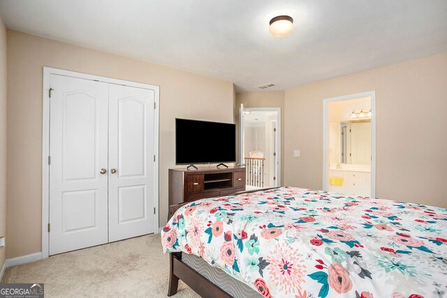 bedroom featuring ensuite bath, light carpet, and a closet