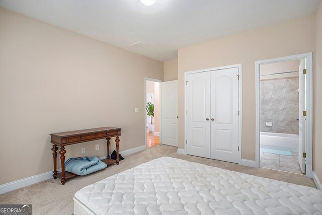 bedroom featuring light carpet, ensuite bathroom, and a closet