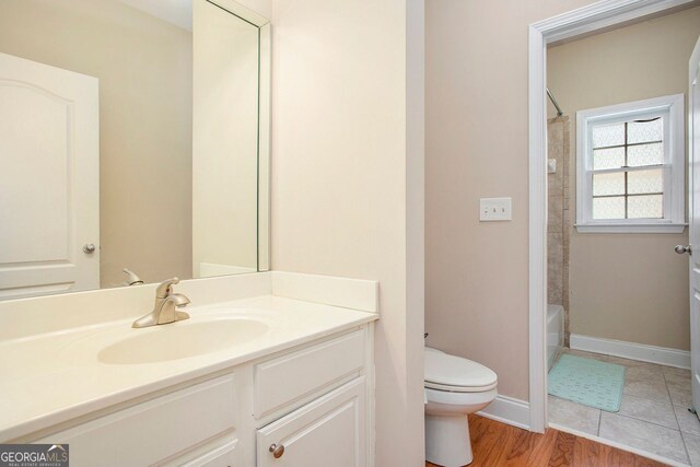 full bathroom with hardwood / wood-style floors, vanity,  shower combination, and toilet