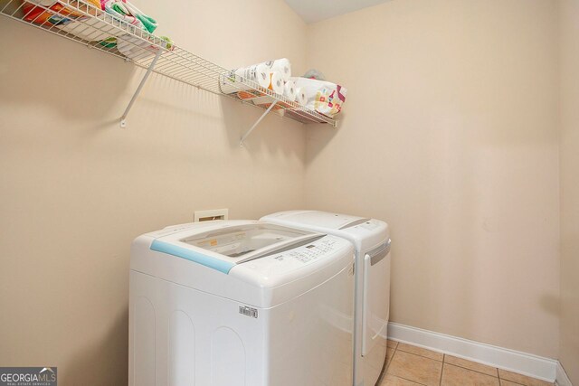 laundry room with independent washer and dryer and light tile patterned flooring