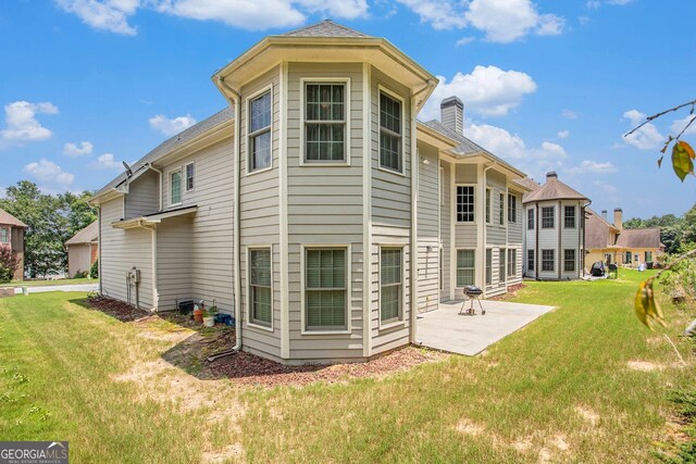 back of house featuring a lawn and a patio