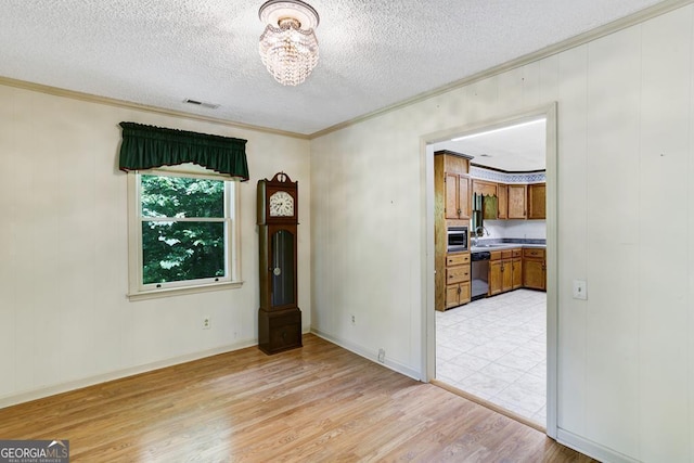 unfurnished room with sink, light hardwood / wood-style flooring, ornamental molding, a textured ceiling, and a chandelier