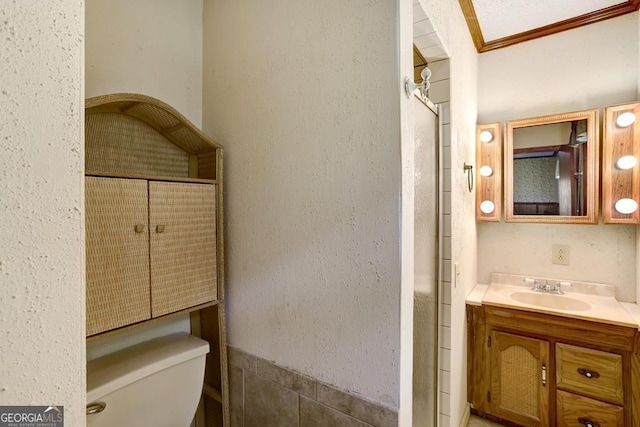 bathroom featuring a shower, vanity, toilet, and crown molding