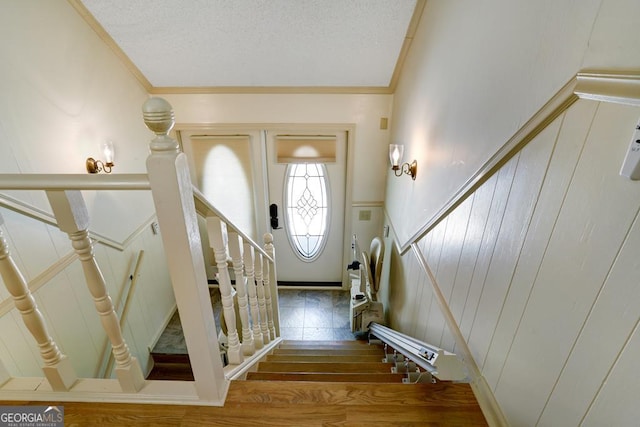 entryway with wood-type flooring, a textured ceiling, and ornamental molding