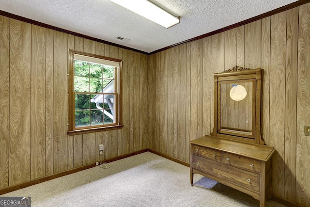 misc room featuring a textured ceiling, light colored carpet, crown molding, and wooden walls