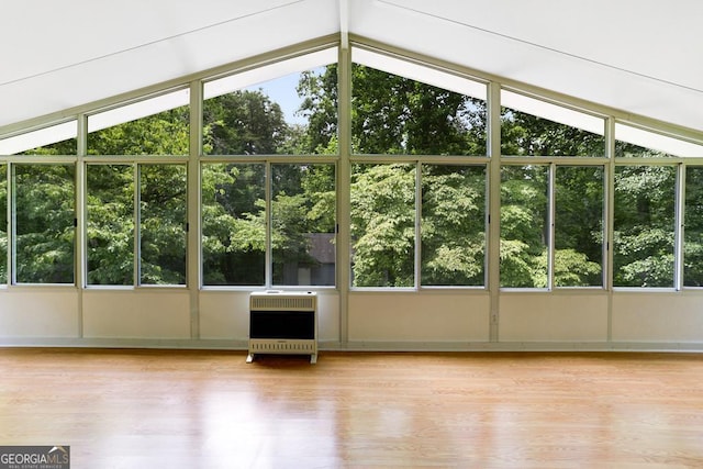 unfurnished sunroom with heating unit, vaulted ceiling, and a wealth of natural light