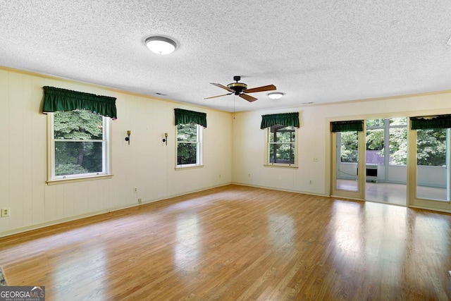 empty room featuring a textured ceiling, light hardwood / wood-style floors, plenty of natural light, and ceiling fan